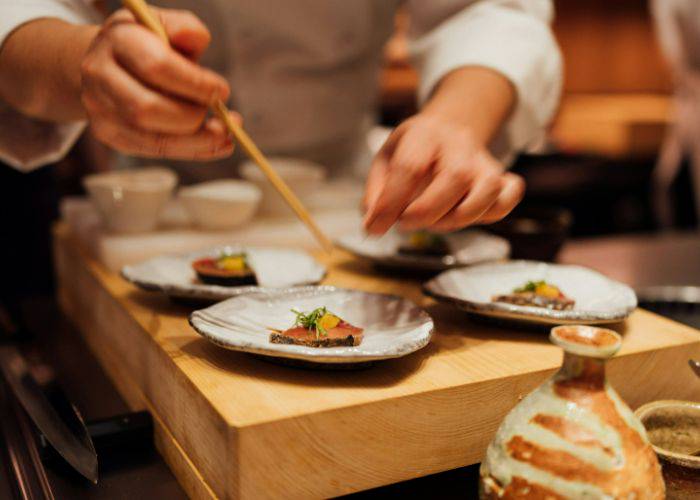 A chef making the final touches to an omakase serving platter.